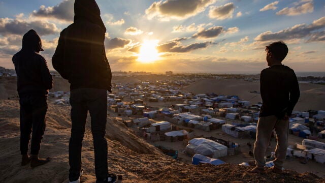 Palestinos observan la puesta de sol en el sur de la Franja de Gaza