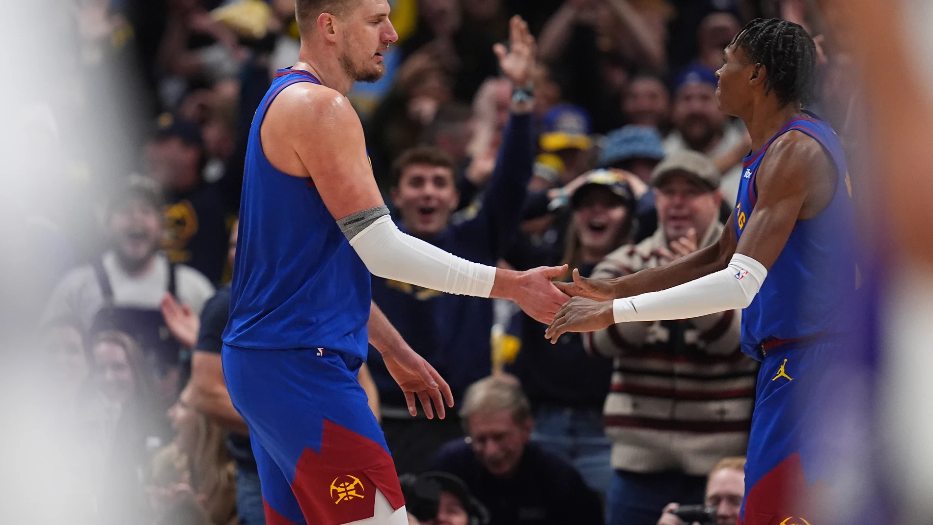 Denver Nuggets center Nikola Jokic, left, is congratulated after making a 3-point basket from 75 feet away as time ran out in the third quarter by forward Peyton Watson in an NBA basketball game against the Sacramento Kings Thursday, Jan. 23, 2025, in Denver. (AP Photo/David Zalubowski)