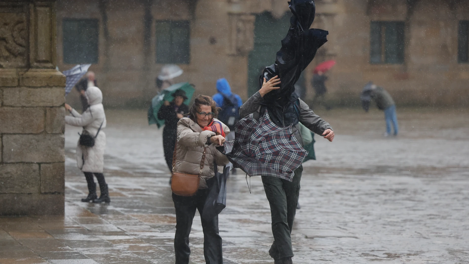 Turistas hoy domingo en la plaza del Obradoiro en Santiago de Compostela. Un potente temporal asociado a la borrasca Herminia va a azotar con fuerza a la península, con lluvias muy intensas y generalizadas, viento con rachas huracanadas por encima de los 20 kilómetros por hora en algunos puntos y aviso rojo en Galicia, donde las olas pueden alcanzar 10 metros de altura hoy en Santiago de Compostela. EFE/Lavandeira jr.