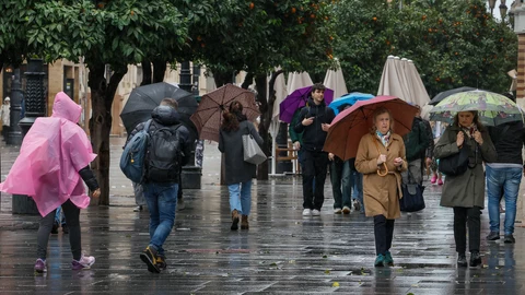 Personas con paraguas caminan por Sevilla por las lluvias