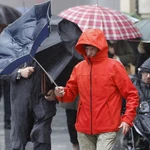 Un hombre trata de protegerse de la lluvia y el viento