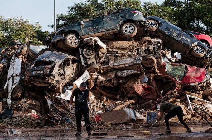 Varias personas limpian entre coches amontonados en Alfafar, a 5 de noviembre de 2024, en Valencia, Comunidad Valenciana (España). Hoy, se cumple una semana desde que la DANA arrasara la Comunitat Valenciana. Hasta el momento, hay 211 víctimas mortales y cuantiosos daños materiales en alrededor de 70 municipios de la provincia de Valencia, desde donde todavía hoy se siguen retirando enseres, vehículos y haciendo achiques de agua. Se ha restablecido ya el 98% del servicio eléctrico y el 93% de la población afectada ya dispone de suministro agua. Feria Valencia ha destinado siete pabellones, su Centro de Eventos y sus cocinas a diversas tareas logísticas y humanitarias para luchar contra los efectos de la DANA que ha afectado a la Comunitat Valenciana. 05 NOVIEMBRE 2024;DANA;RIADA;AFECTADOS;VALENCIA;COMUNIDAD VALENCIANA;DESTRUCCIÓN;ESCOMBROS;BASURA; Carlos Luján / Europa Press 05/11/2024