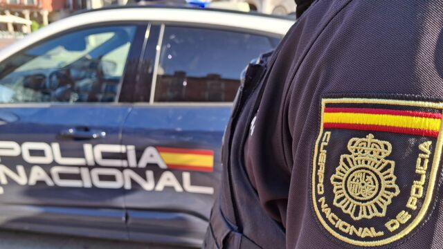 Un agente de la Policía Nacional junto a un coche patrulla