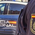 Un agente de la Policía Nacional junto a un coche patrulla