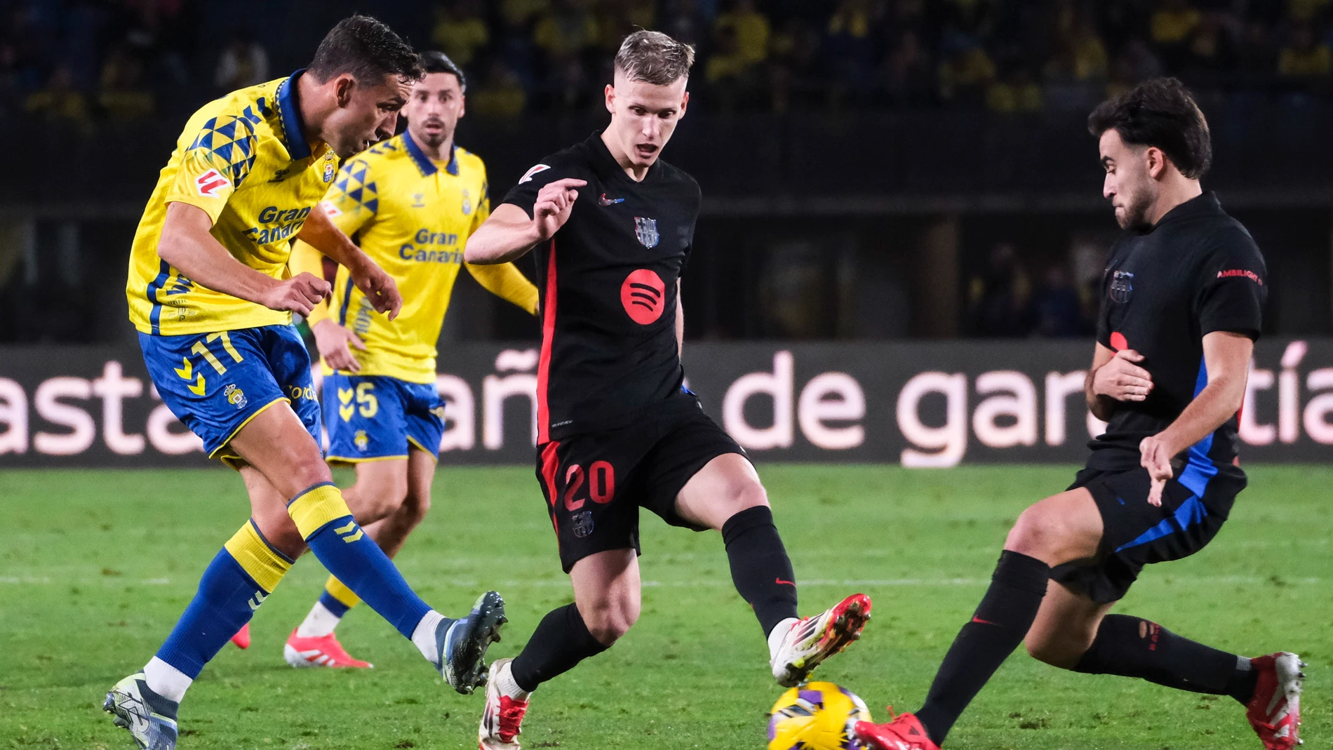 Las Palmas de Gran Canaria, 22/02/2025.- El delantero de la UD Las Palmas, Jaime Mata (i), remata ante los jugadores del FC Barcelona, Eric García (d) y Dani Olmo, durante el encuentro correspondiente a la jornada 25 de Laliga EA Sports que disputan hoy sábado en el estadio de Gran Canaria. EFE / Angel Medina G.
