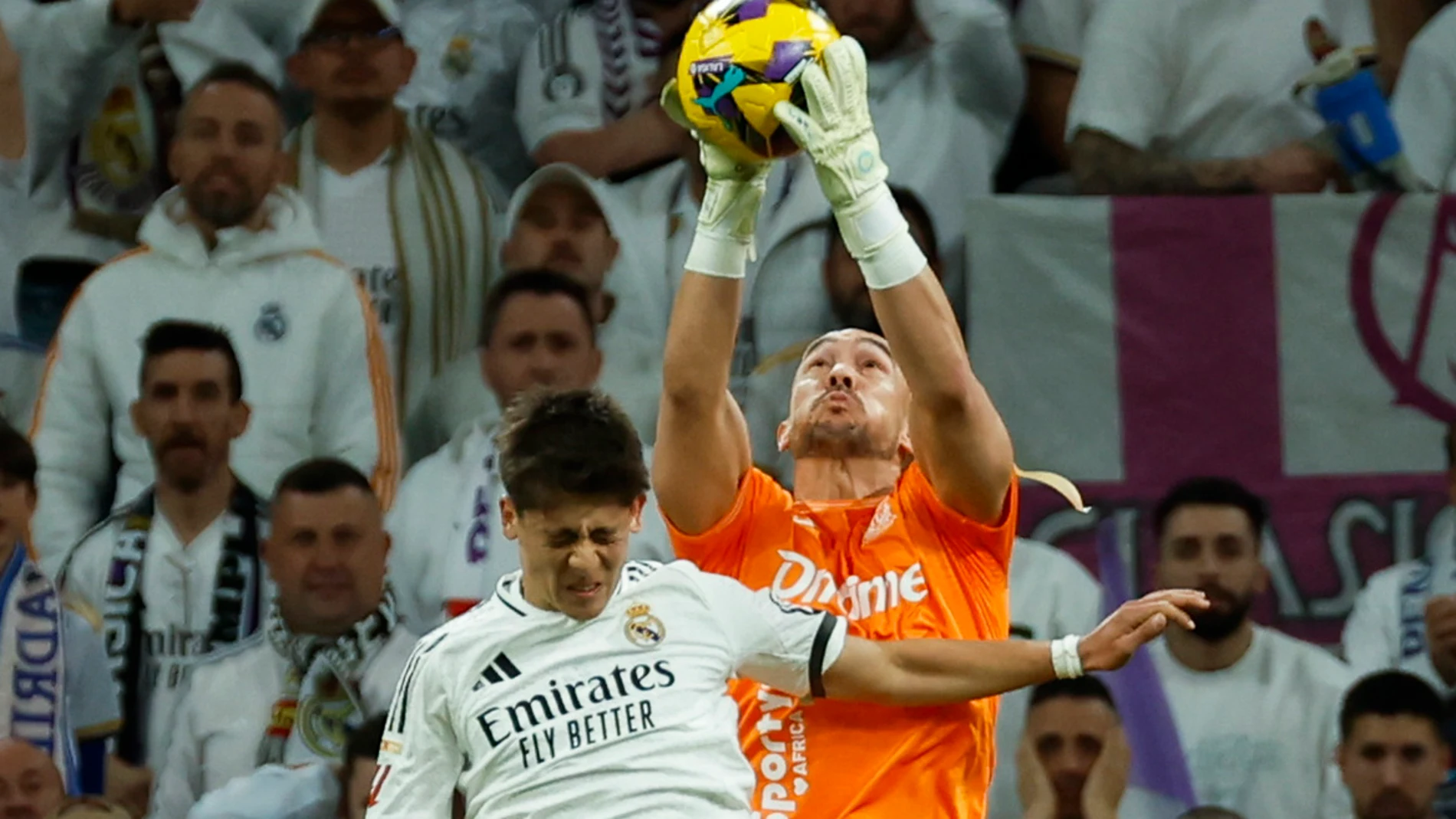 MADRID, 29/03/2025.- El guardameta del Leganés Marko Dmitrovic bloca un balón junto al turco Arda Guler, del Real Madrid, durante el partido de la jornada 29 de LaLiga que Real Madrid y CD Leganés disputan este sábado en el estadio Santiago Bernabéu. EFE/Mariscal