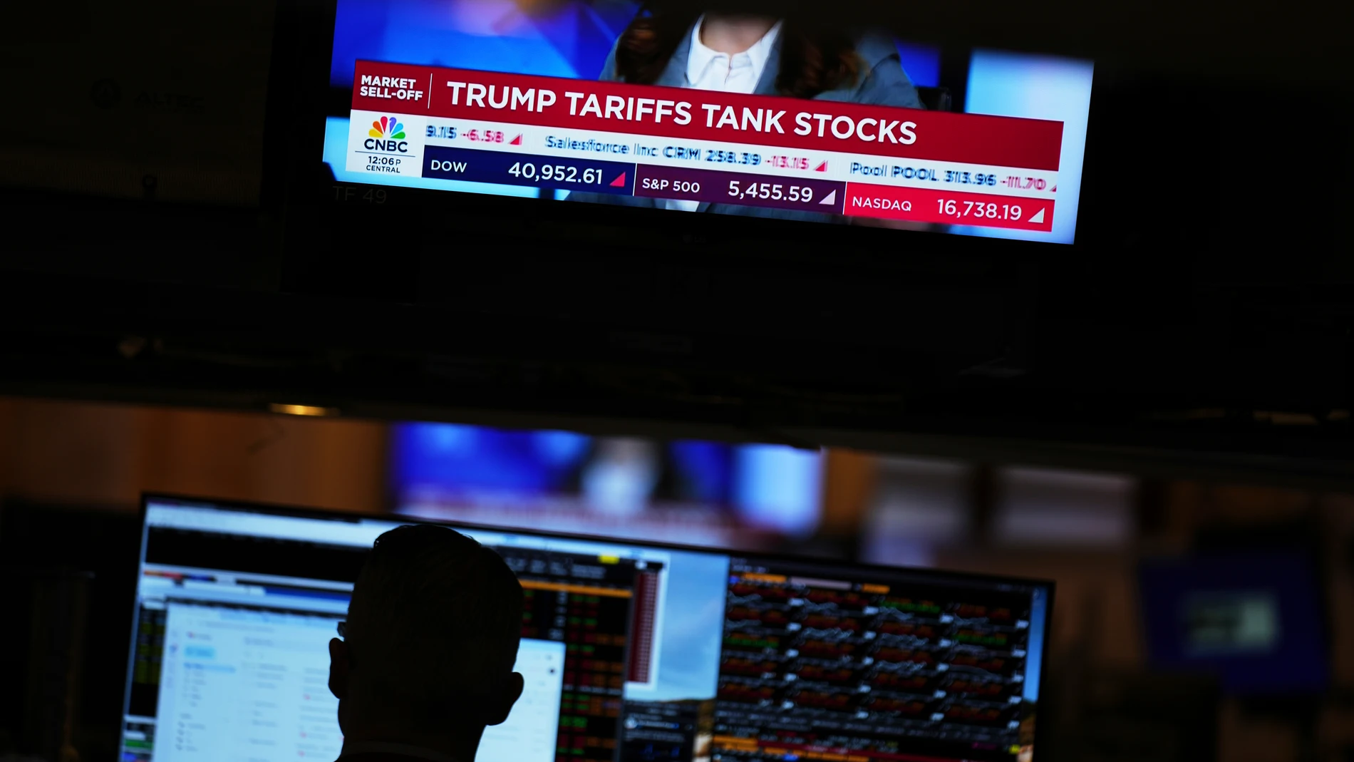 A screen displays financial news as traders work on the floor at the New York Stock Exchange in New York, Thursday, April 3, 2025. (AP Photo/Seth Wenig)