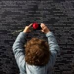 Una mujer hace una foto del nombre de su familiar, colocado en un panel junto a los nombres de las demás víctimas de la fosa de Pico Reja