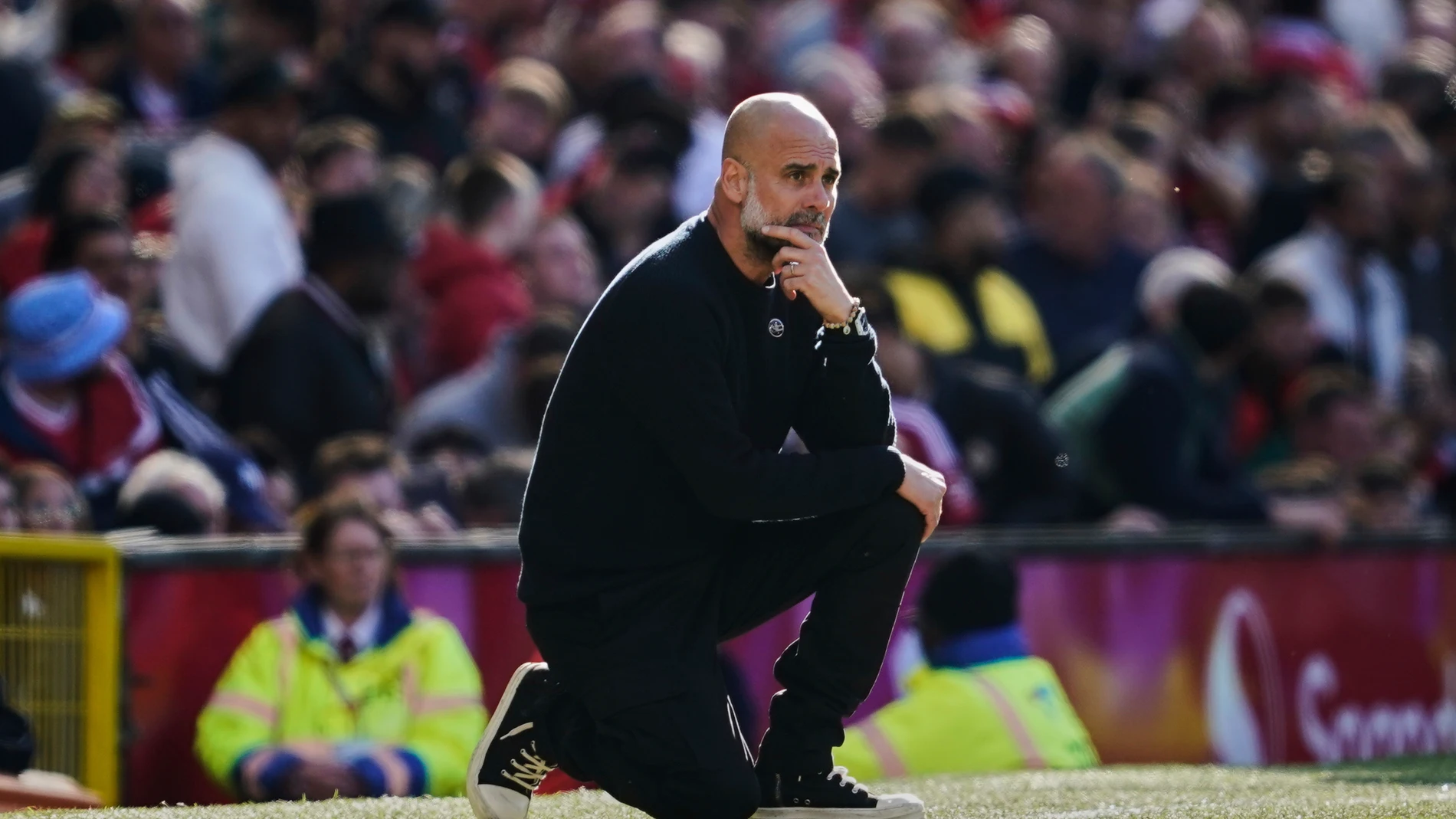 Manchester City's head coach Pep Guardiola kneels on the sideline during the English Premier League soccer match between Manchester City and Manchester United in Manchester, England, Sunday, April 6, 2025. (AP Photo/Dave Thompson)
