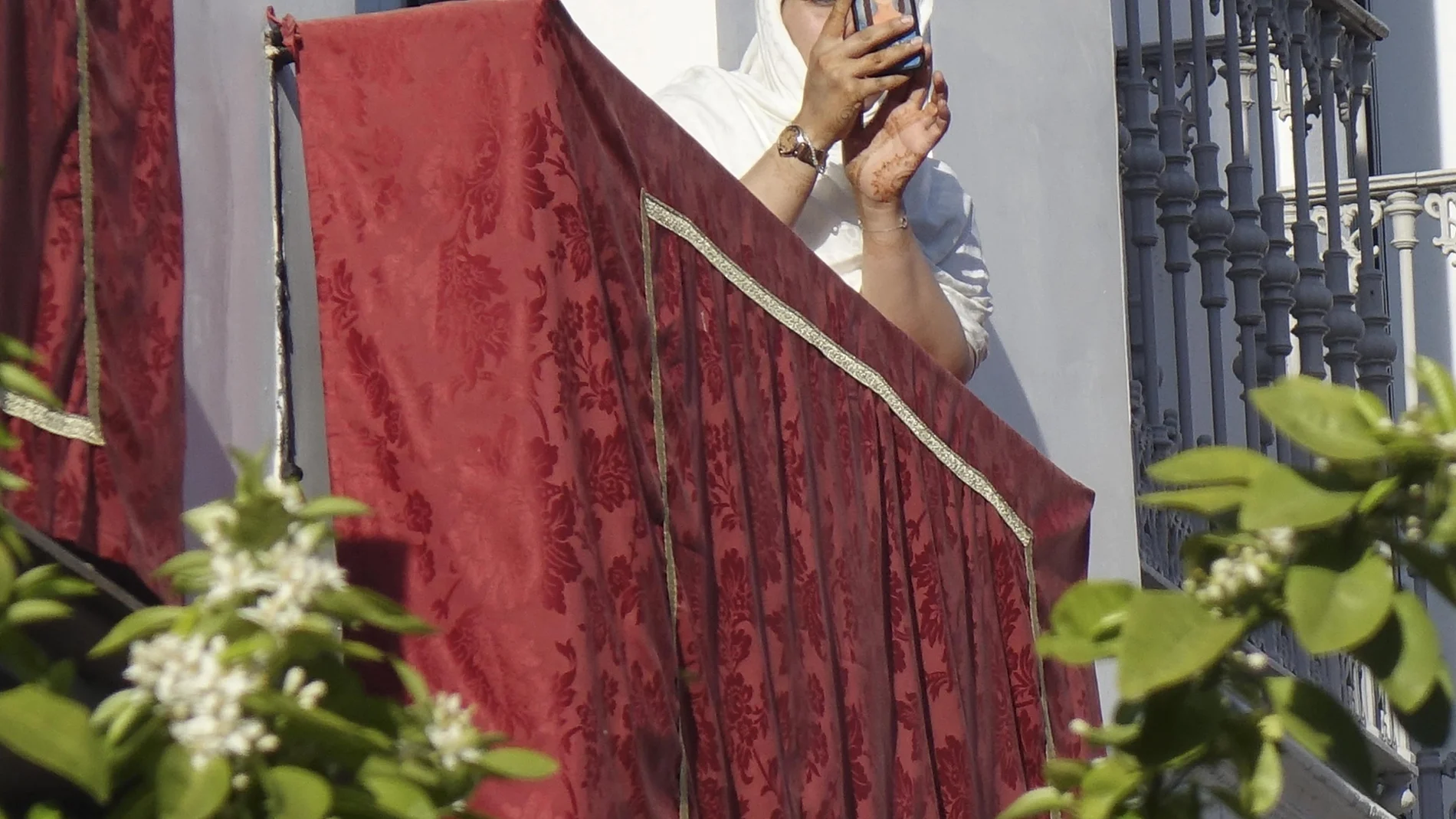 Una turista fotografía un desfile procesional desde un balcón