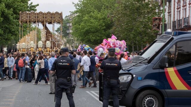 Dos agentes de la Policía Nacional vigilan el paso de Palío de la Virgen María Santísima del Refugio de la Hermandad de San Bernardo a su salida de este popular barrio sevillano.