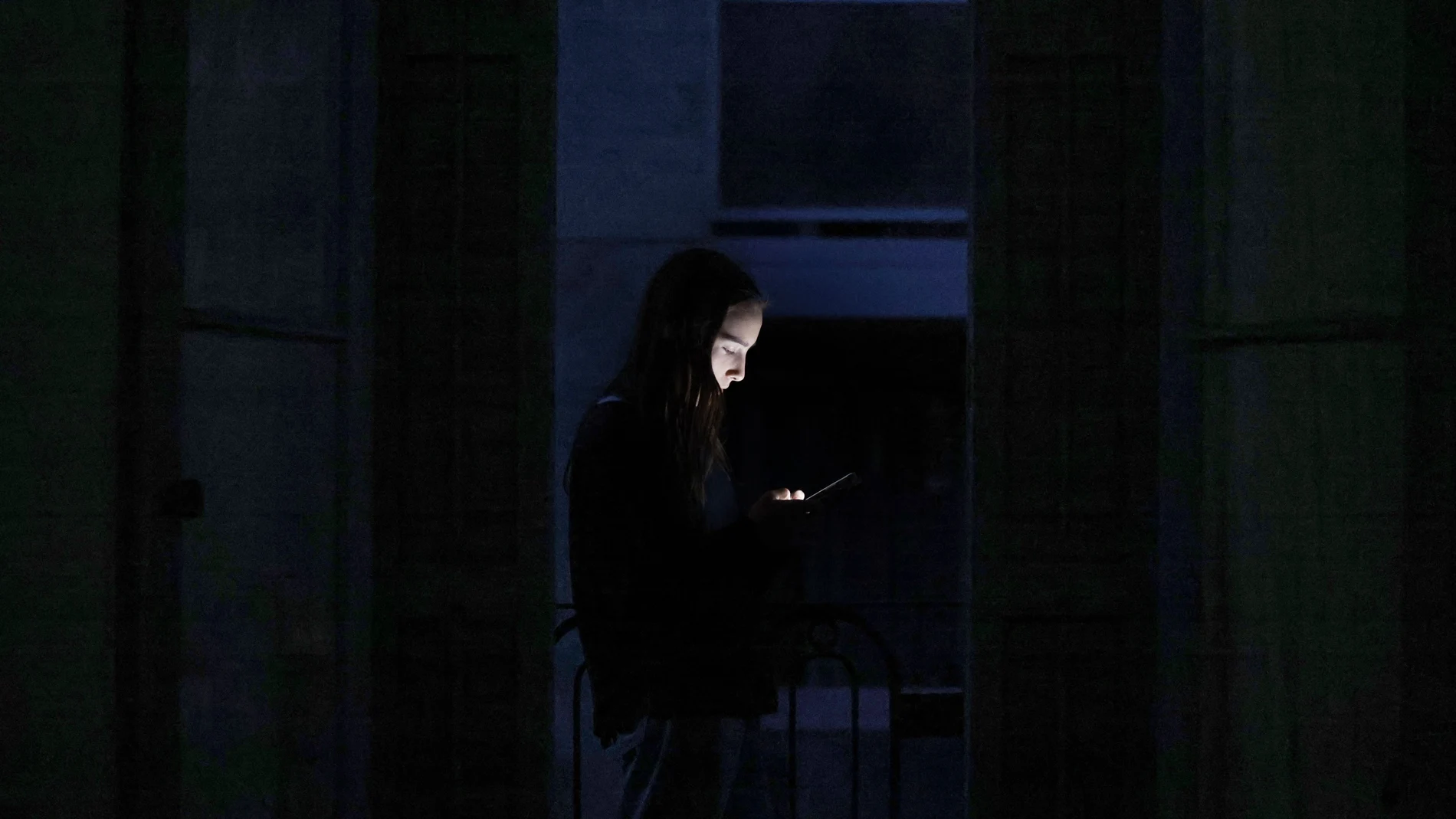 GRAFCAT7635. BARCELONA, 28/04/2025.- Un joven consulta su teléfono móvil en un balcón mientras gran parte de Barcelona continúa sin luz debido al corte de suministro eléctrico que afecta este lunes a España y que ha dejado sin servicio el metro y el tranvia de Barcelona y todas las líneas de ferrocarril en Barcelona, y sin red de teléfonos móviles ni internet. EFE/Alberto Estévez