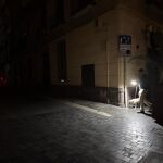 Un vecino del centro de Málaga pasea a su perro con una linterna en las inmediaciones de la Plaza de la Merced, una zona que no recuperó la electricidad hasta las 00:00 del martes