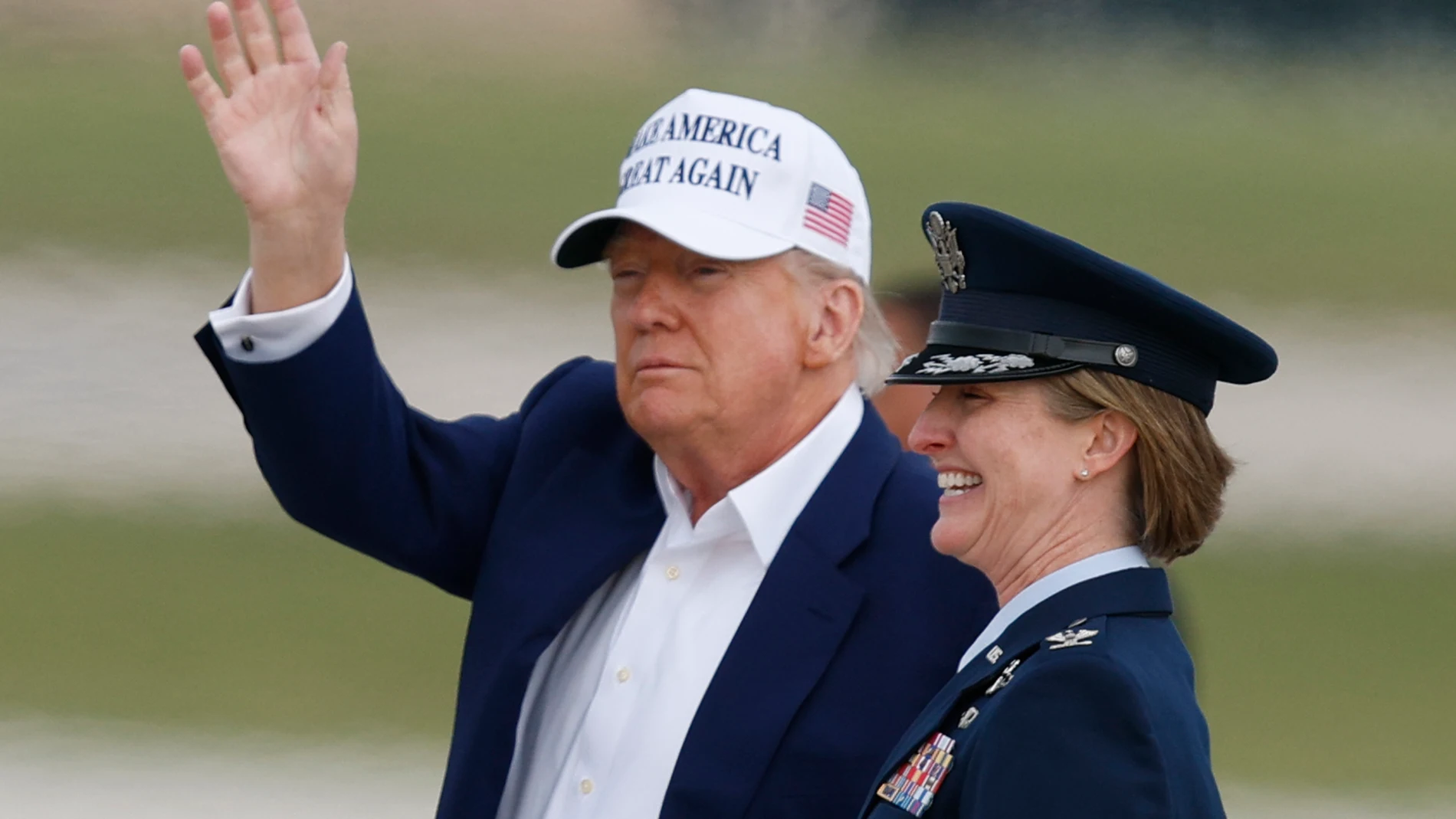 President Donald Trump waves as he is escorted by Air Force Col. Angela F. Ochoa, Commander, 89th Airlift Wing, as he walks from Air Force One before boarding Marine One, upon his arrival at Joint Base Andrews, Md., Sunday, May 25, 2025. (AP Photo/Luis M. Alvarez)