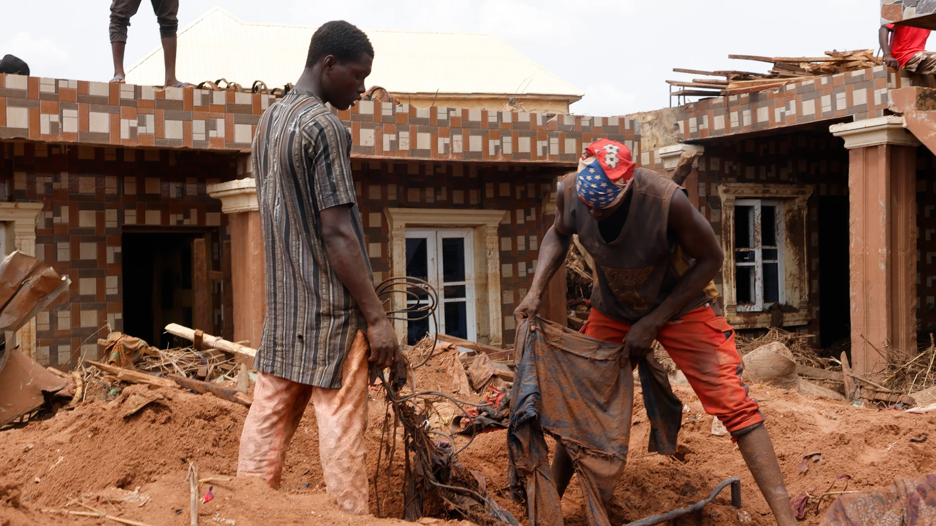Varias personas buscan en una zona inundada tras las fuertes lluvias caídas en la localidad de Mokwa, estado de Níger, Nigeria
