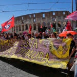 Manifestantes pasan junto al Coliseo con una pancarta donde se lee "levantemos las manos contra el estado del miedo"
