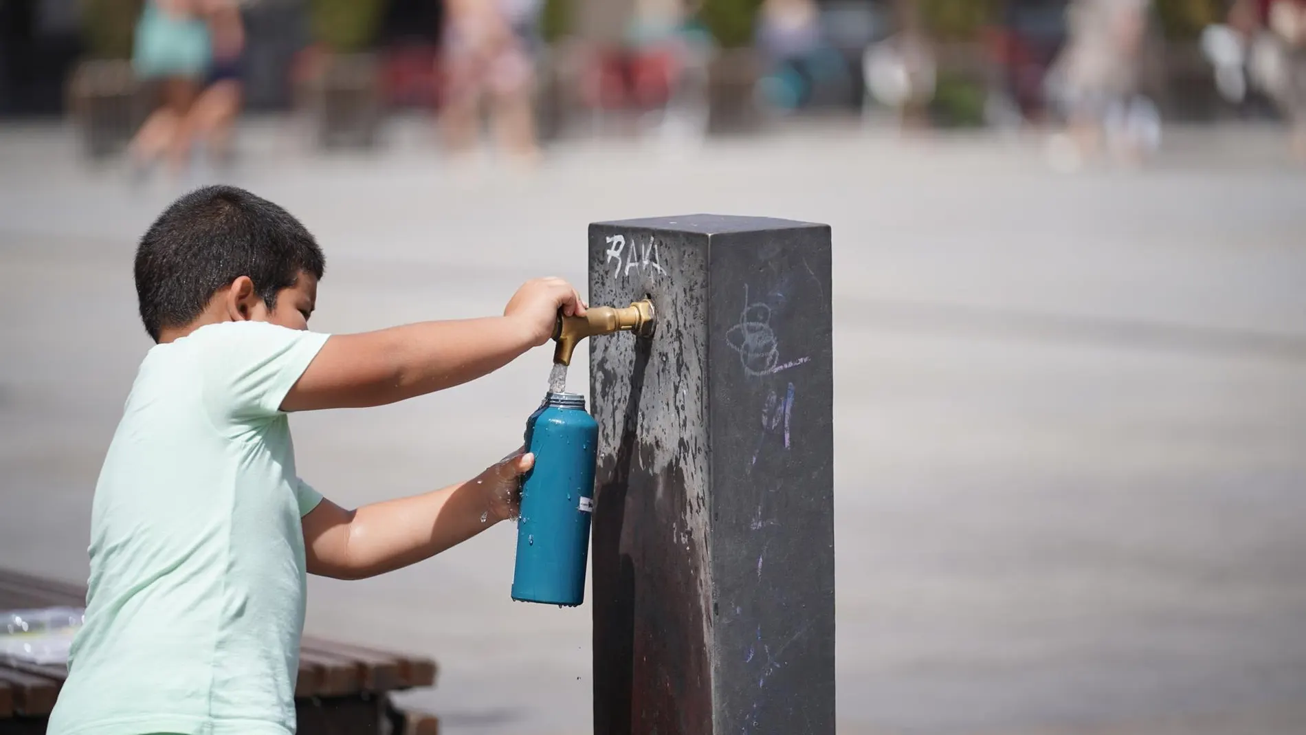 Un menor se refresca en una fuente
