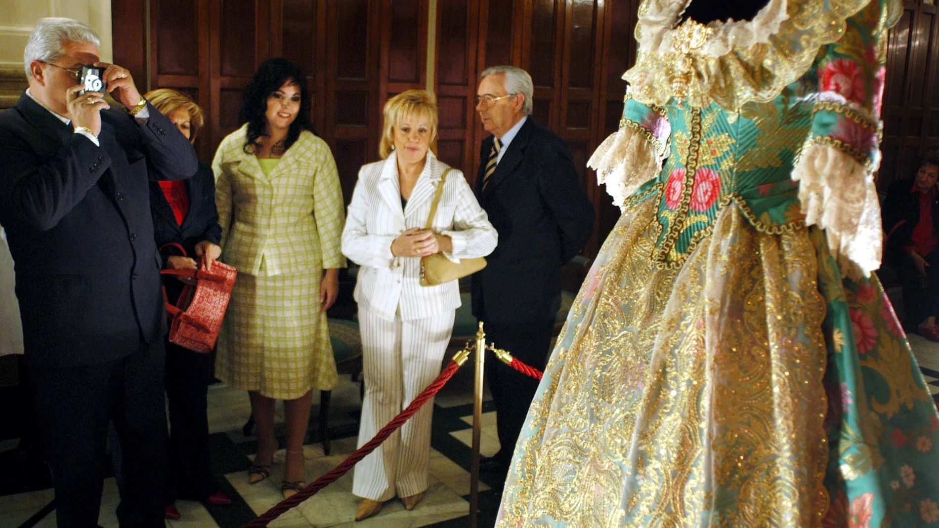 Varias personas fotografían y contemplan el traje confeccionado por el indumentarista Enrique Marzal como regalo de boda para la entonces prometida del Príncipe Felipe, Letizia Ortiz