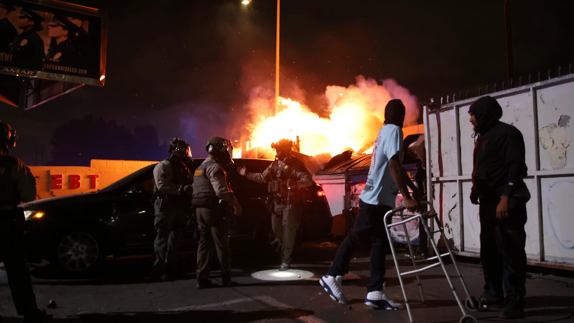 A man looks back at a fire after law enforcement helped him out of a car during a protest in Compton, Calif., Saturday, June 7, 2025, after federal immigration authorities conducted operations. (AP Photo/Ethan Swope)