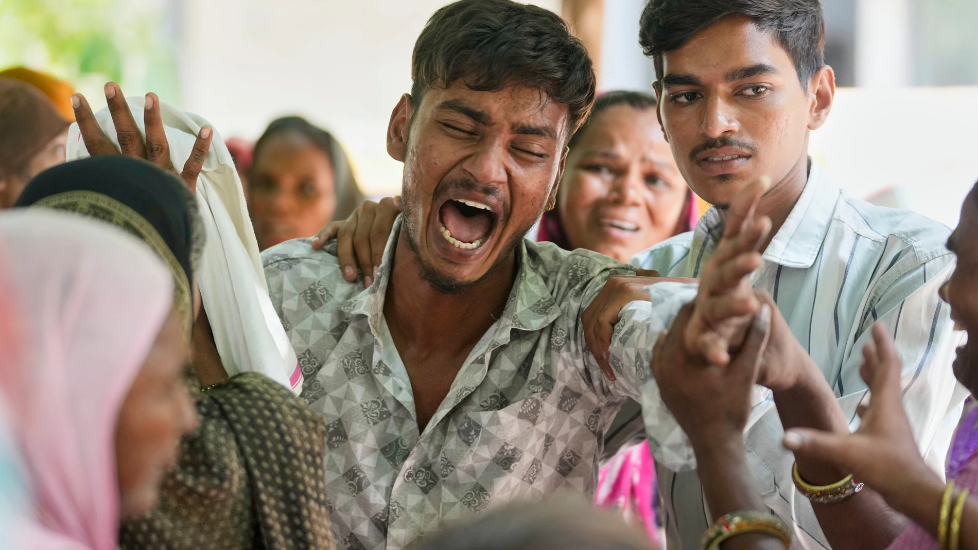 A relative of a victim of Thursday's Air India plane crash is comforted as he breaks down at a hospital in Ahmedabad, India, Saturday, June 14, 2025. (AP Photo/Rafiq Maqbool)