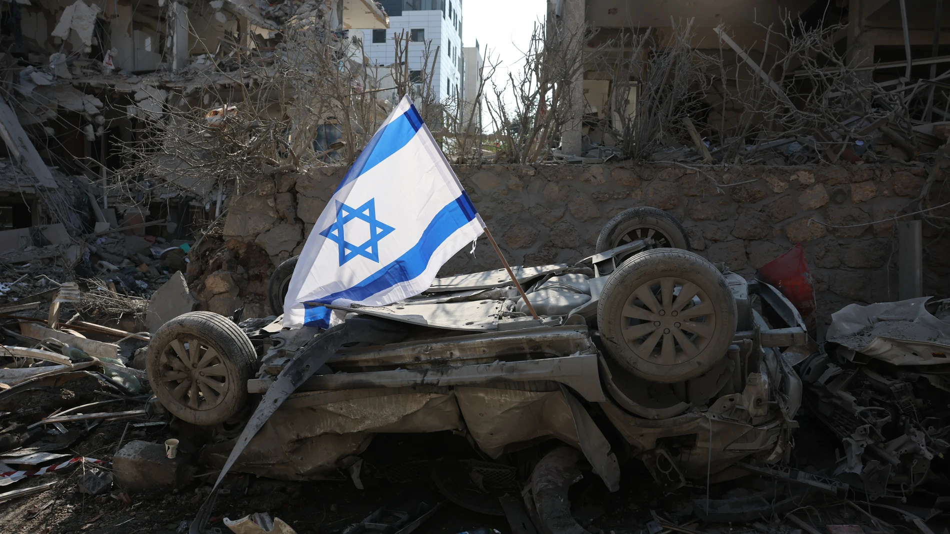 Ramat Gan (Israel), 14/06/2025.- An Israeli flag placed over a damaged car after a ballistic missile strike in a residential area in Ramat Gan, near Tel Aviv, Israel, 14 June 2025. Israel's military said Iran launched dozens of missiles and drones toward Israel, with some intercepted. Magen David Adom (MDA), Israel's national emergency services, reported at least three killed and dozens of injured, including some in critical condition, in the retaliatory attacks. Israel launched strikes on Ir...