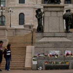 James Harnan, a la izquierda, y Jane Faragher, a la derecha, visitan un monumento improvisado en memoria de la diputada del estado de Minnesota Melissa Hortman y su marido Mark en el Capitolio del estado,
