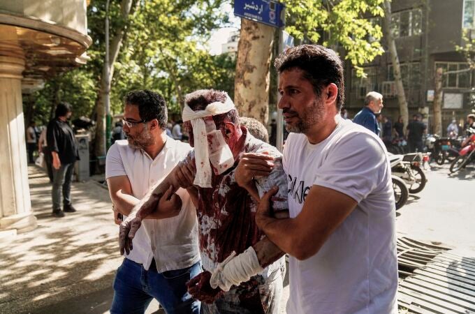 Un hombre herido es ayudado a abandonar el lugar de los hechos tras una explosión en el centro de Teherán, en medio de la campaña de ataques de Israel