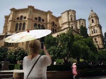 Una señora con un paraguas fotografía la Catedral durante la ola de calor