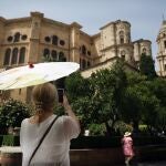 Una señora con un paraguas fotografía la Catedral durante la ola de calor