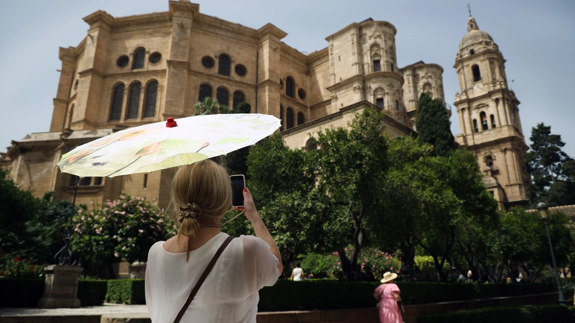 Una señora con un paraguas fotografía la Catedral durante la ola de calor