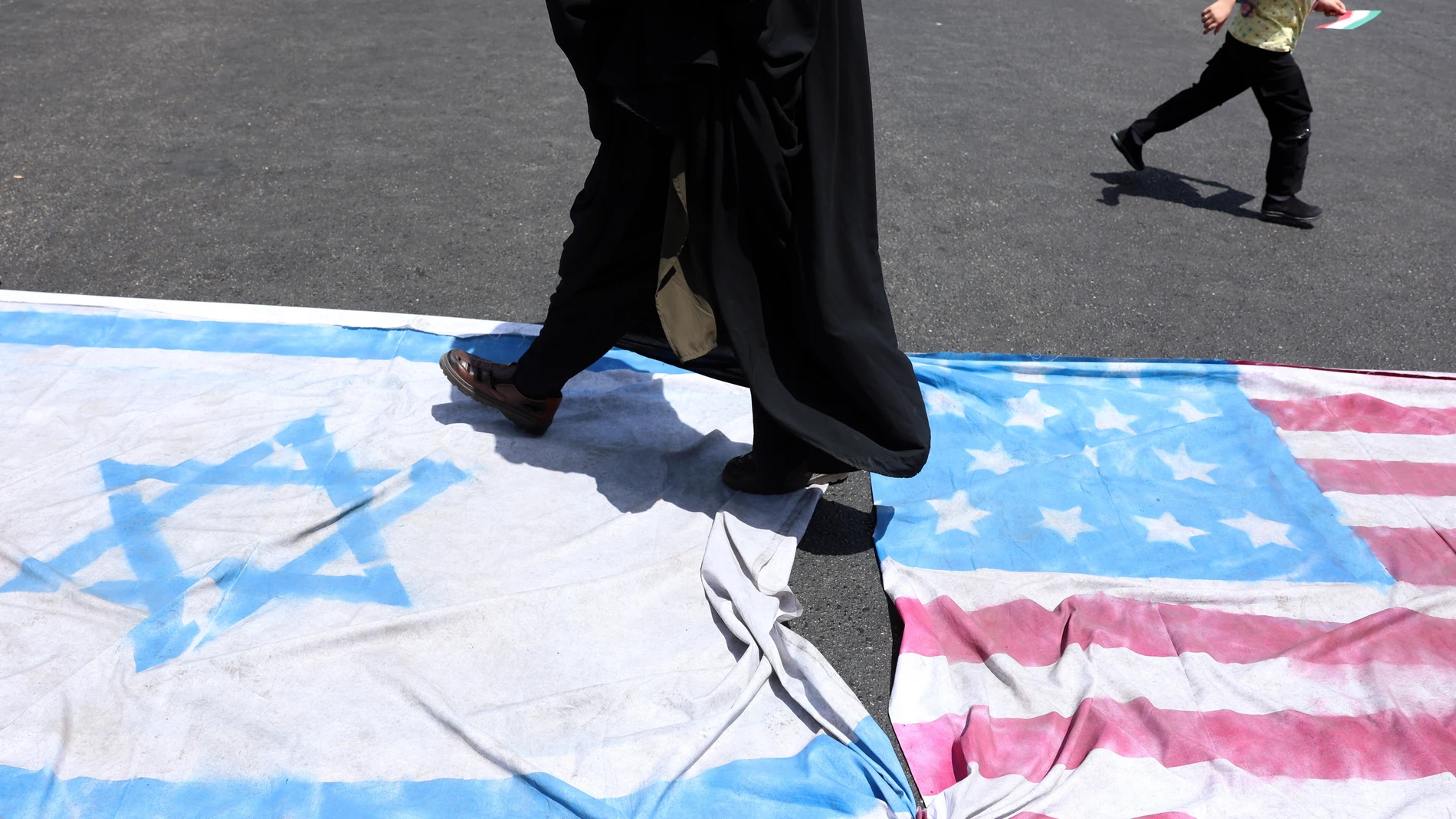 TEHRAN (IRAN (Islamic Republic Of)), 20/06/2025.- Iranians walk on Israeli and US flags during an anti-Israel rally in Tehran, Iran, 20 June 2025. Israel and Iran have been exchanging fire since Israel launched strikes across Iran on 13 June 2025 as part of Operation 'Rising Lion.' (Protestas, Teherán) EFE/EPA/ABEDIN TAHERKENAREH