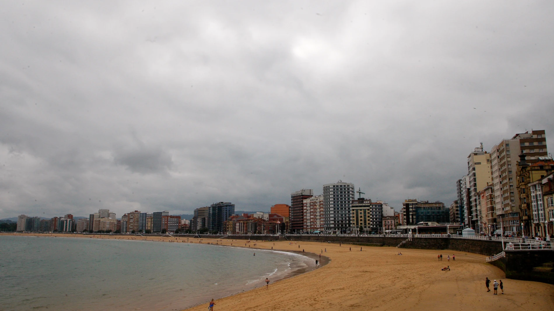 GIJÓN (ASTURIAS), 23/06/2025.- La Playa de San Lorenzo, en Gijón, este lunes en una jornada en la que Asturias está en alerta amarilla por lluvias que podrían dejar 15 litros por metro cuadrado en una hora y por tormentas que podrían ser de granizo y rachas muy fuertes de viento. EFE/Juan González