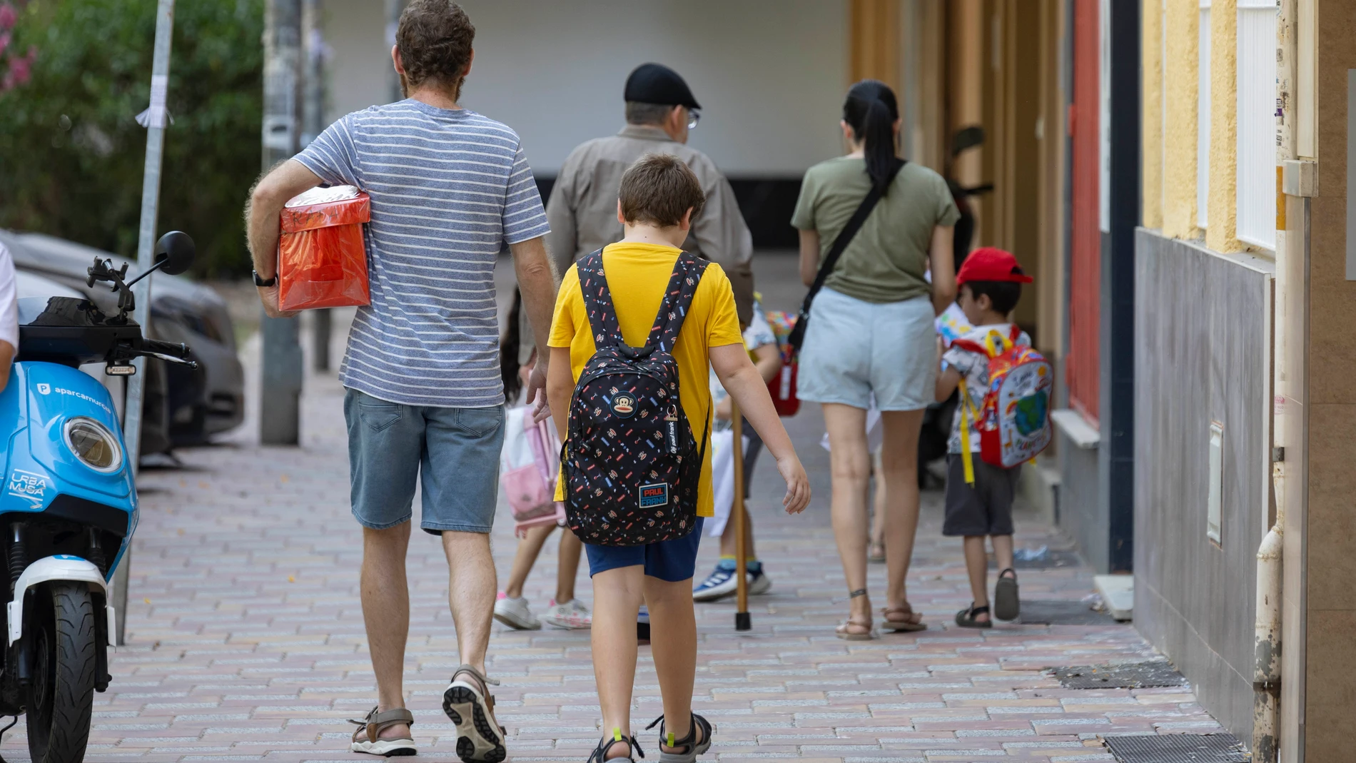 MURCIA, 23/06/2025.- Un padre junto a su hijo a la salida de un colegio de Murcia. Los escolares del municipio de Murcia terminarán las clases este martes 24 de junio y no regresarán a las aulas hasta el próximo 8 de septiembre, un total de once semanas de vacaciones que generan numerosos quebraderos de cabeza a las familias, que tienen que hacer un importante esfuerzo económico que oscila, de media, entre los 250 y 350 euros al mes. En el caso de Murcia capital, la oferta municipal directame...