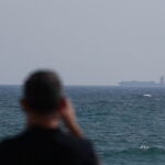Una persona mira el tránsito de un barco por el estrecho de Ormuz