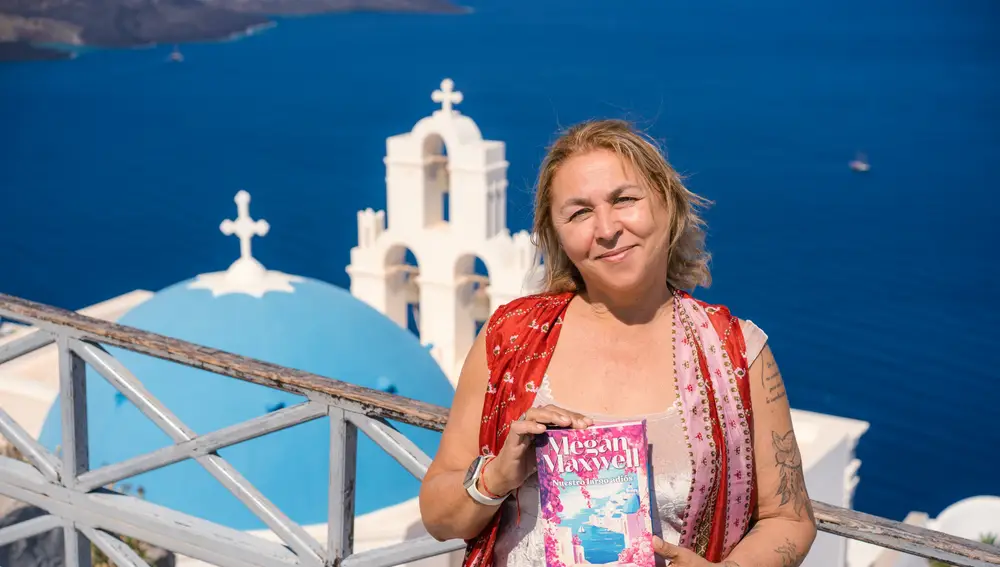 Maxwell con su libro delante de una de las reconocibles cúpulas azules de Santorini