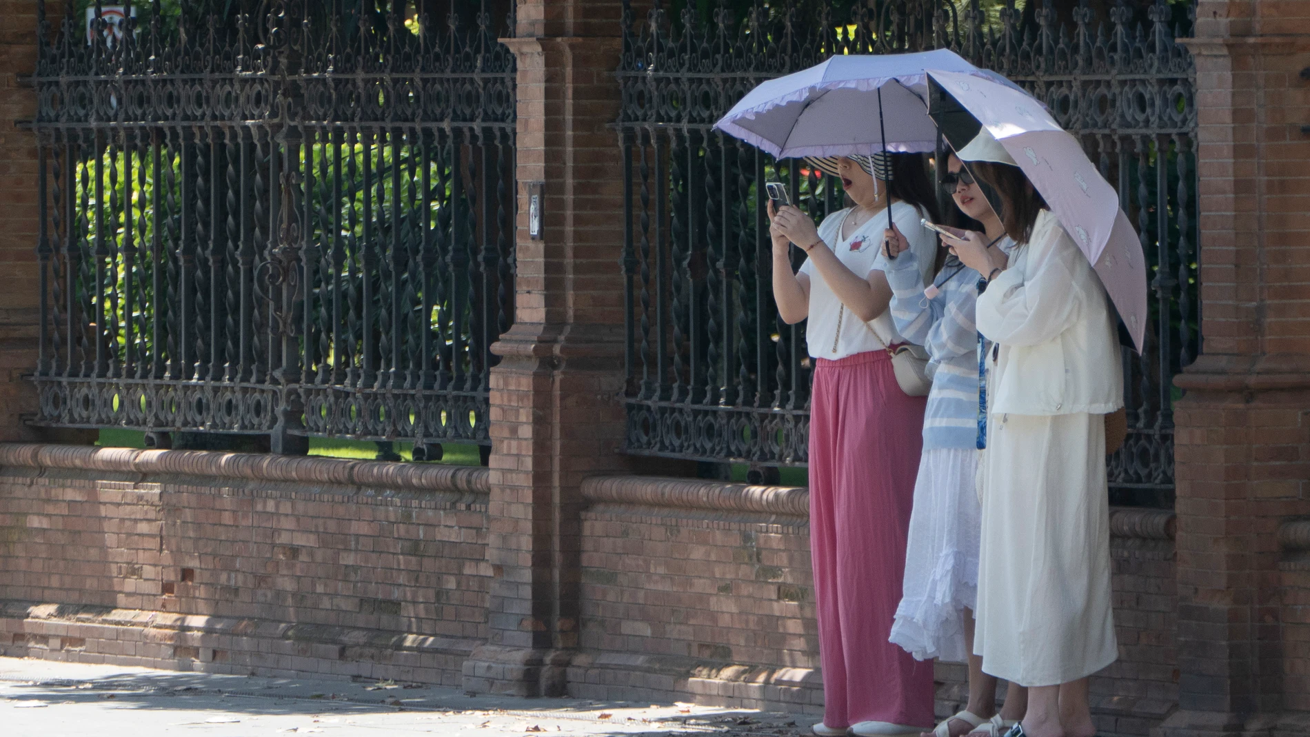 Varias mujeres se protegen del sol este domingo