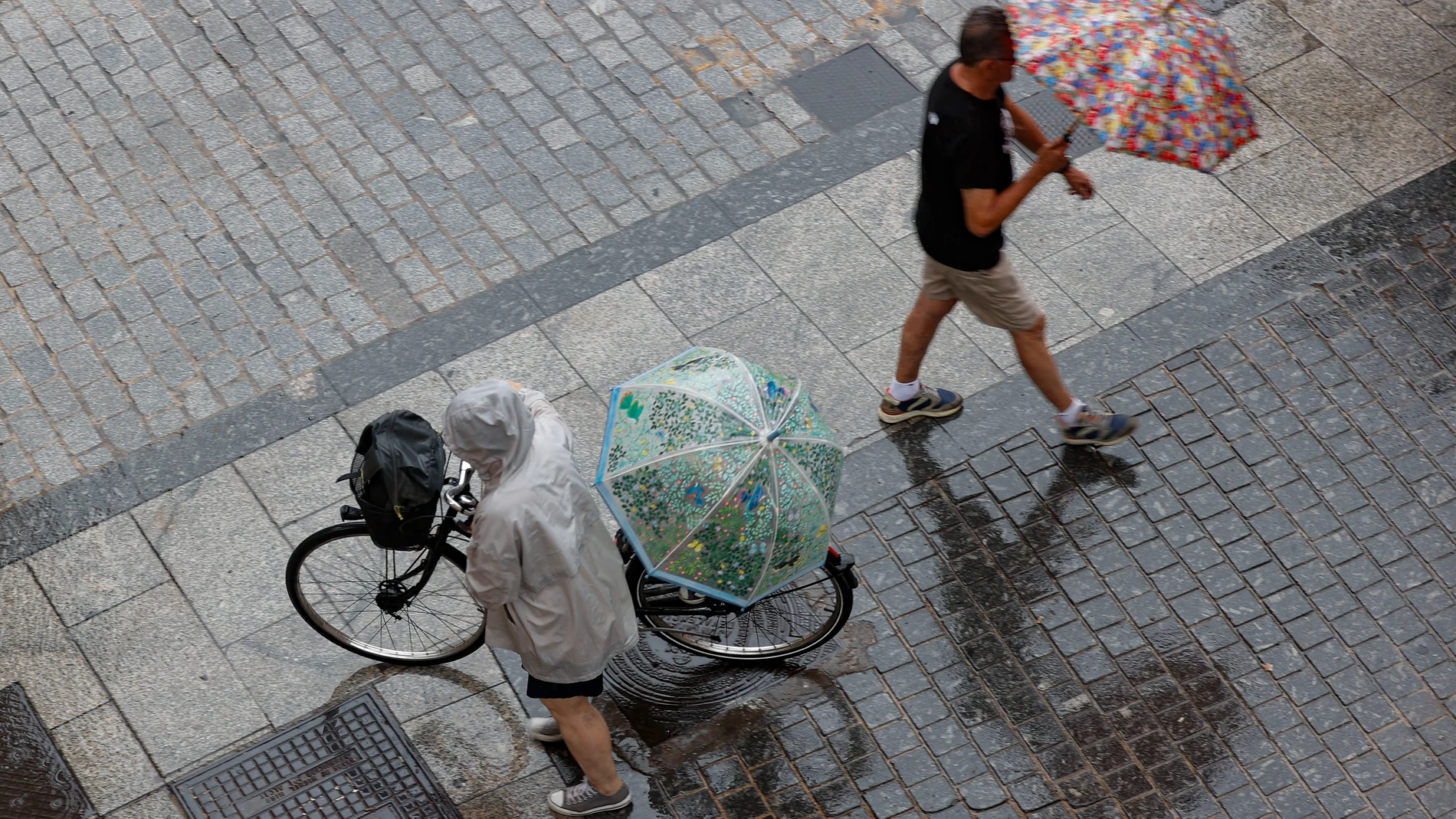 GRAFCVA8625. VALÈNCIA, 12/07/2025.- La lluvia que ha caído desde la madrugada en Castellón y el norte de Valencia se ha extendido al área metropolitana de València. Una decena de comunidades de la mitad norte y el tercio este peninsular se encuentran este sábado en alerta por riesgo de lluvia y tormentas. En la imagen dos personas caminan bajo la lluvia en una calle de València este sábado. EFE/Manuel Bruque