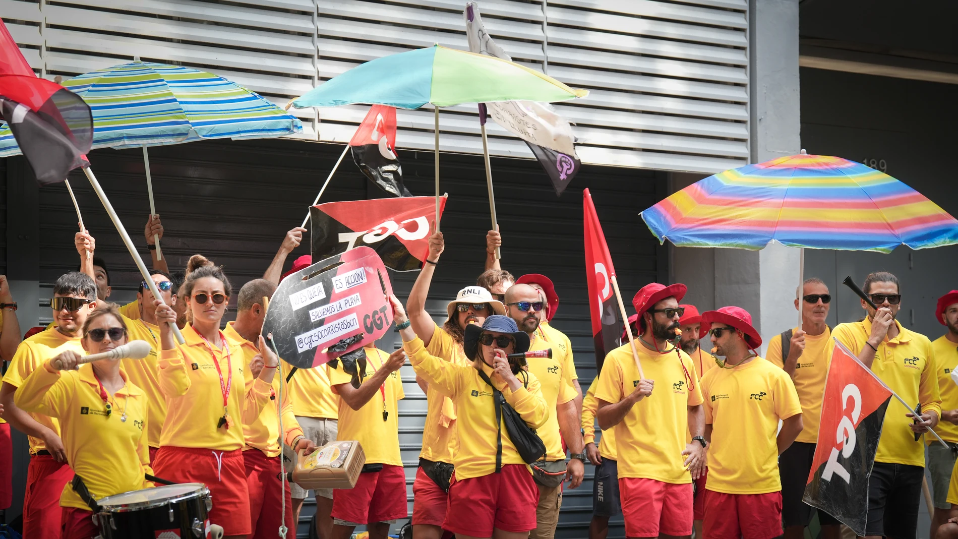 Varias personas protestan durante la huelga indefinida de los socorristas en Barcelona, frente a la sede del PSC, a 4 de agosto de 2025, en Barcelona, Catalunya (España). Desde el 1 de agosto de 2025 los socorristas de las playas de Barcelona mantienen una huelga indefinida, convocada por el sindicato CGT, en plena temporada alta del verano. La protesta está dirigida contra la empresa concesionaria del servicio, FCC Medio Ambiente, contratada por el Ayuntamiento de Barcelona, y denuncia una “...