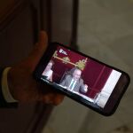 El alcalde de Málaga sujeta un teléfono móvil en el que reproduce el vídeo viral del pleno de julio