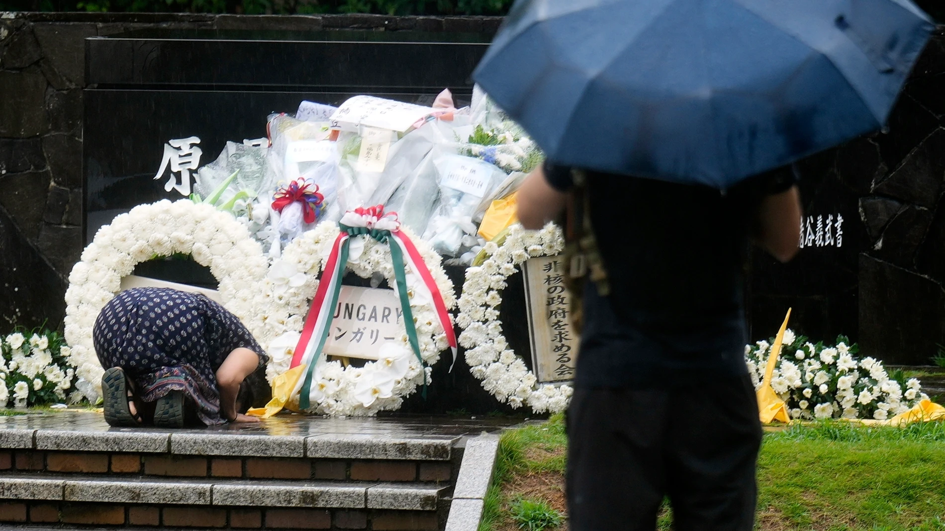 A woman prays during a private ceremony to honor the victims of the atomic bombing and to pray for peace on the 80th anniversary of the bombing at Nagasaki's Hypocenter Park in Nagasaki, western Japan Saturday, Aug. 9, 2025. (AP Photo/Eugene Hoshiko)