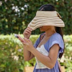 Una turista se tapa con un sombrero la cara. 