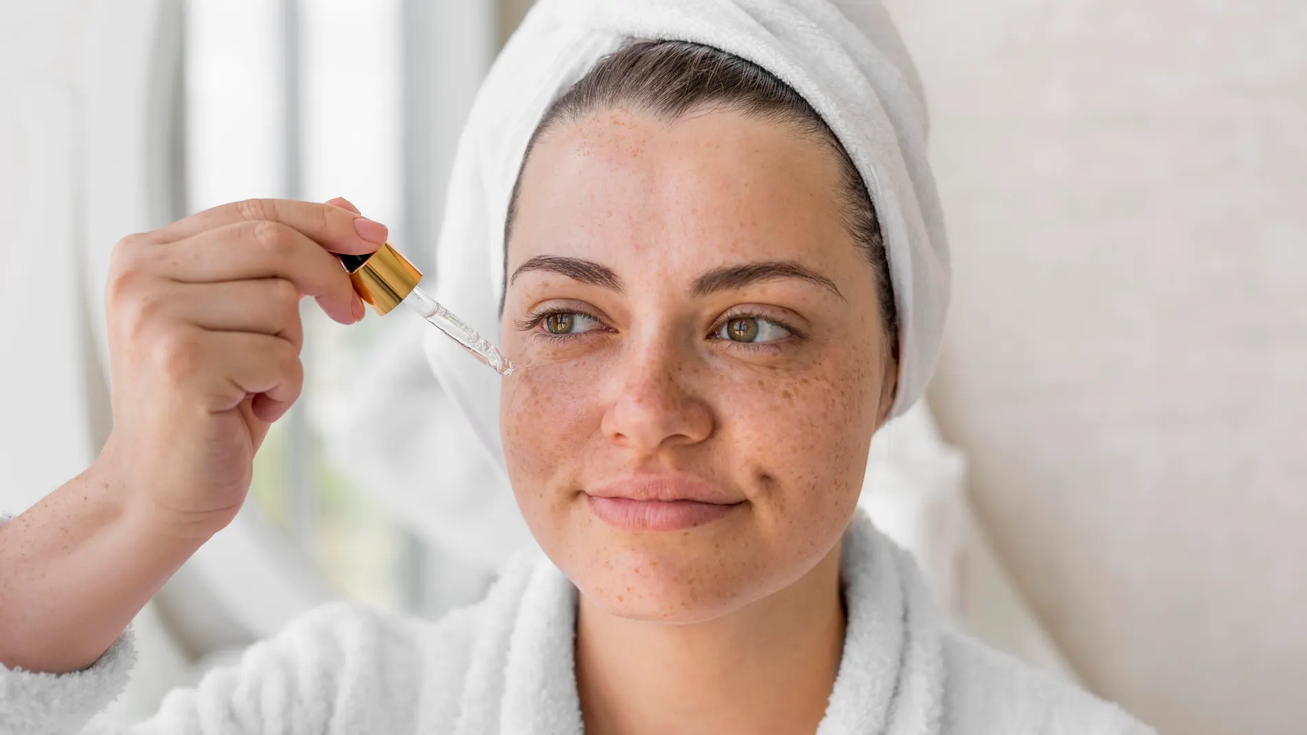 Mujer aplicando sérum facial con gotero para cuidar la piel y prevenir manchas solares.