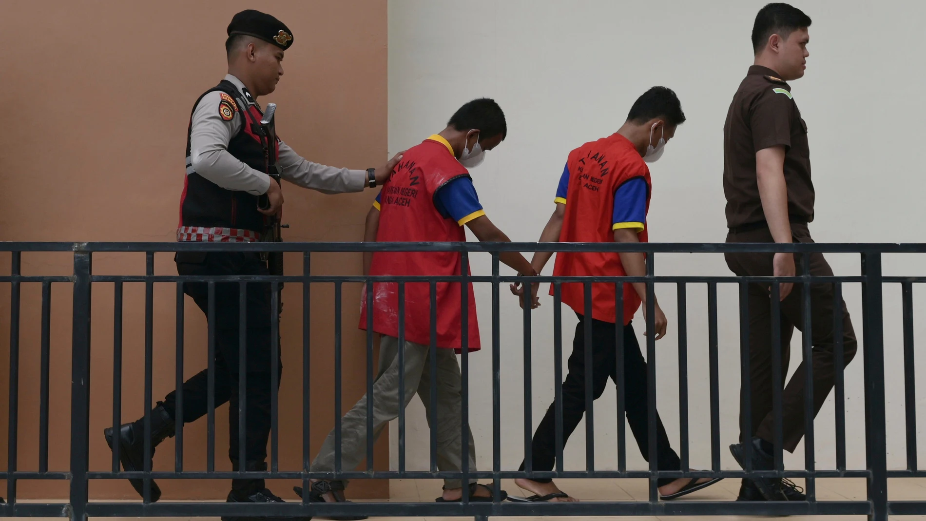 A police officer and a prosecutor escort two men accused of having gay sex, upon arrival for their sentencing hearing at the Sharia Court in Banda Aceh, Indonesia, Monday, Aug. 11, 2025. (AP Photo/Reza Saifullah)