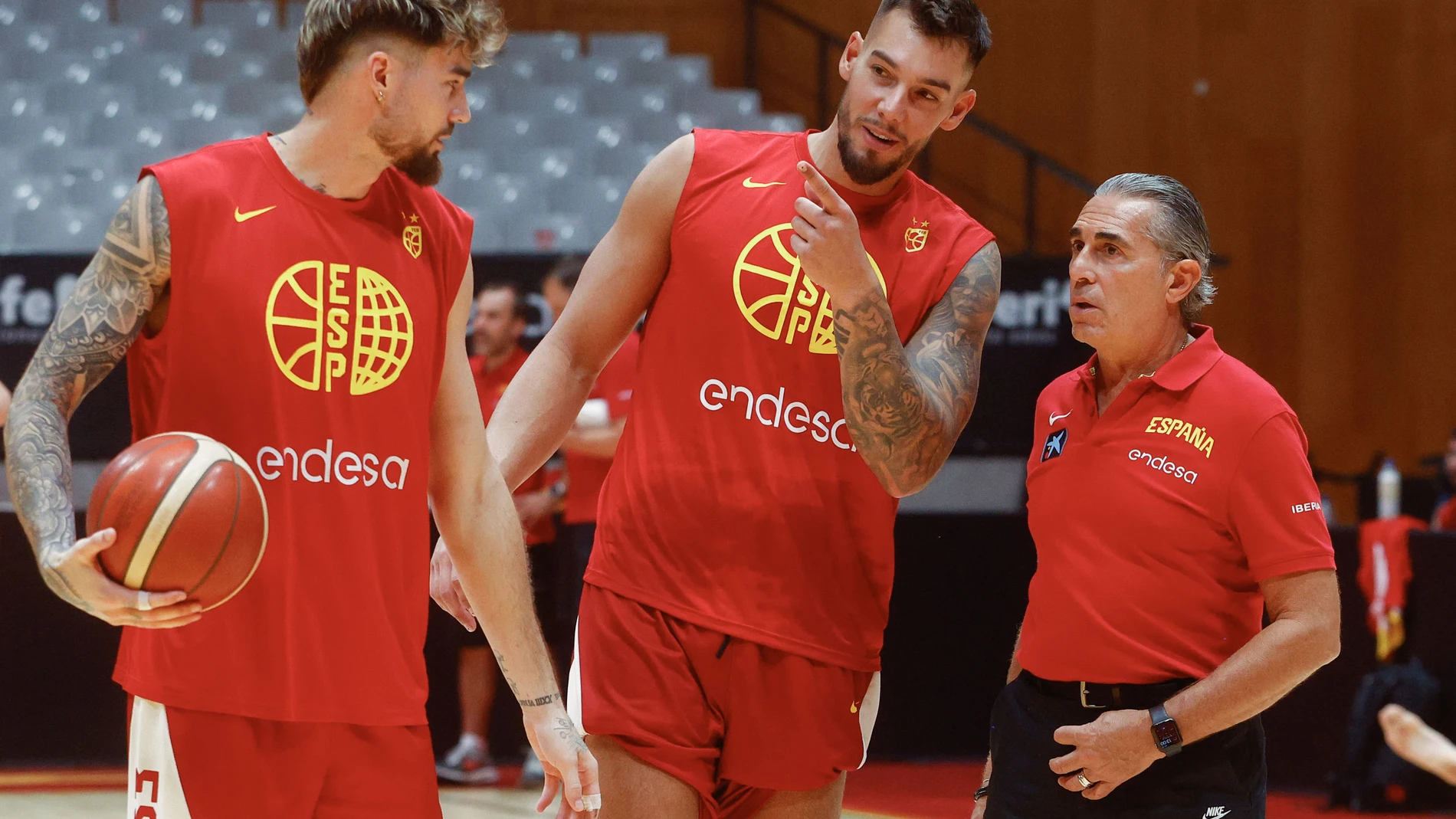 BADALONA (BARCELONA), 13/08/2025.- El seleccionador español de baloncesto, el italiano Sergio Scariolo (d) conversa con los hermanos Hernagómez, Juancho (i) y Willy (c) este miércoles en Badalona en el entrenamiento previo al partido amistoso contra Francia, preparatorio para el próximo Eurobasket. EFE/ Quique García