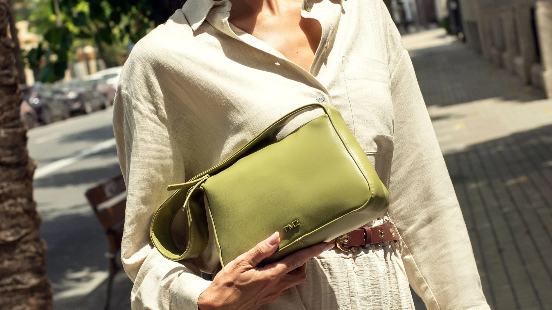 Primer plano de bolso verde de Paco Martínez combinado con vestido camisero beige en un look urbano de día.