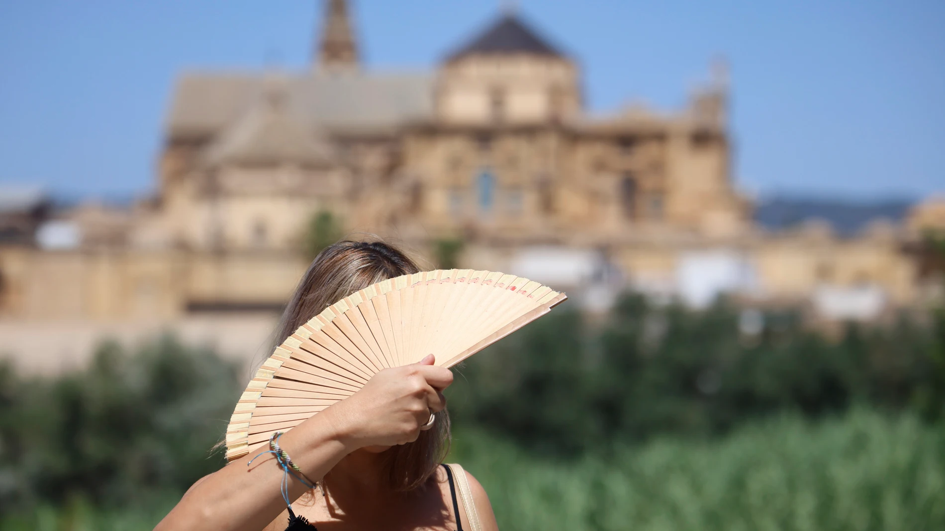 CÓRDOBA, 15/08/2025.- Una turista se abanica en el puente romano de Córdoba este viernes. El puente de agosto comienza con España inmersa en una larga ola de calor. EFE/ Salas