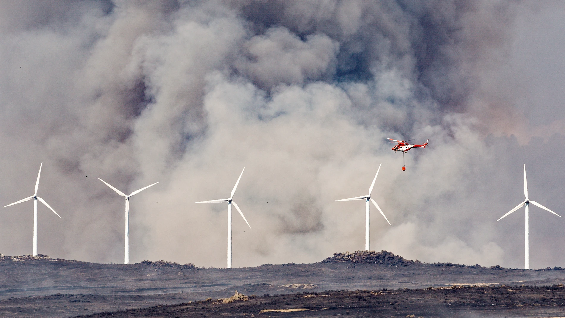 ÁVILA (CASTILLA Y LEÓN), 15/08/2025.- Un helicóptero trabaja este viernes, en labores de extinción del incendio en las proximidades de Urraca-Miguel, barrio anexionado de Ávila capital, y cuyos vecinos han sido evacuados pasadas las 16 horas por la proximidad de las llamas. EFE/ Raúl Sanchidrián