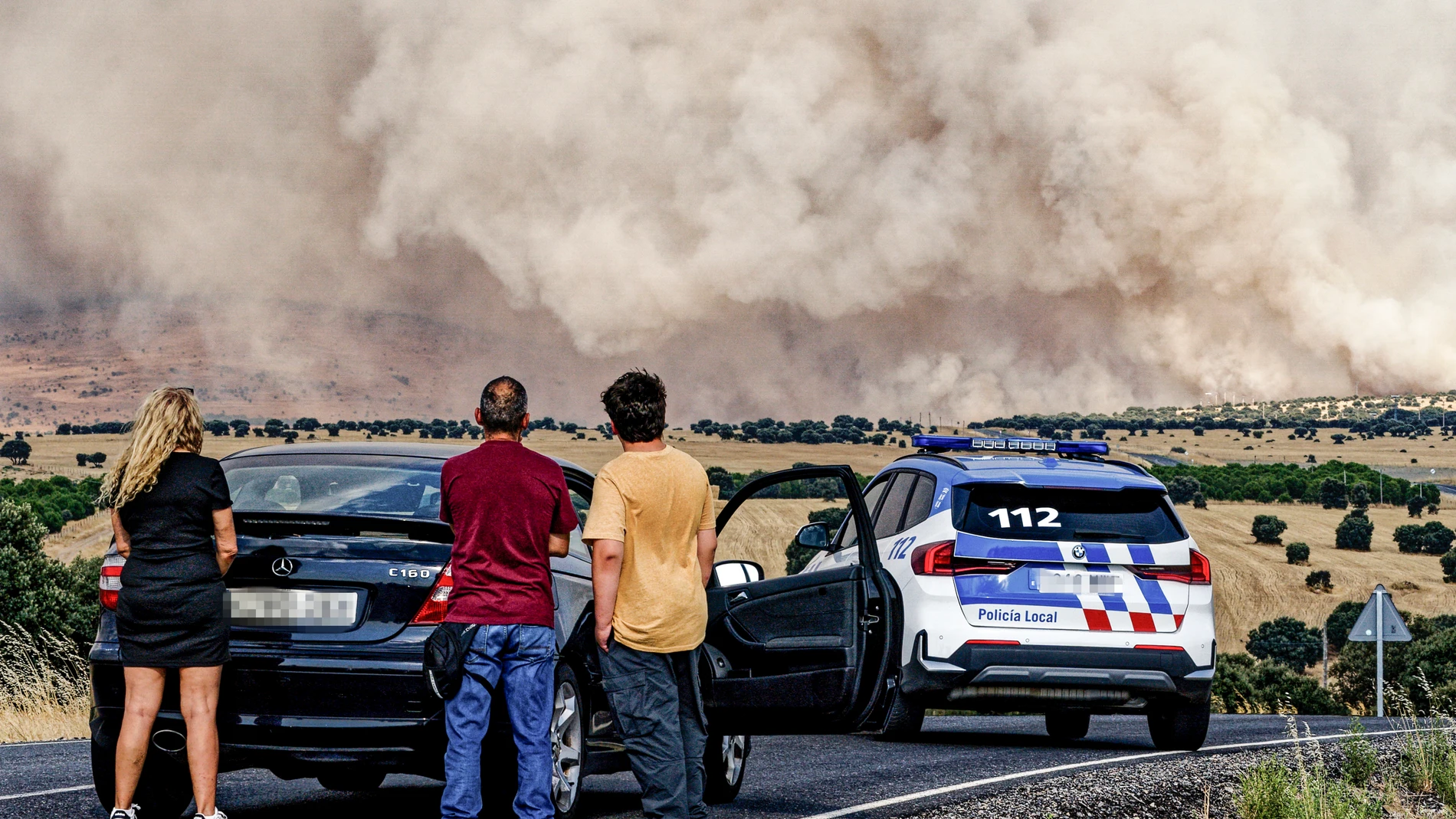 ÁVILA (CASTILLA Y LEÓN), 15/08/2025.- Un grupo de personas paradas en la carretera AV-500, la cual se encuentra cortada en las proximidades de Urraca-Miguel, barrio anexionado de Ávila capital con motivo del incendio que azota la zona este viernes. EFE/ Raúl Sanchidrián
