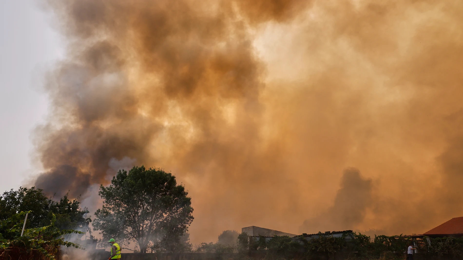 Plumes of smoke rise as a man tries to extinguish a wildfire in Veiga das Meas, northwestern Spain, on Saturday, Aug. 16, 2025. (AP Photo/Lalo R. Villar)