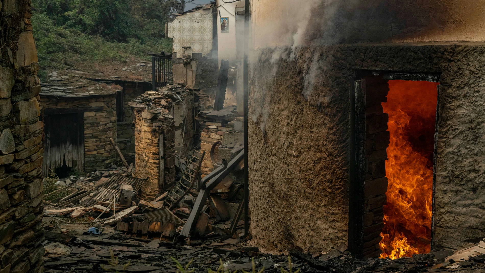 VILAMARTÍN DE VALDEORRAS (OURENSE), 18/08/2025.- Vista de viviendas ardiendo en la aldea de San Vicente, este lunes en Vilamartín de Valdeorras (Ourense). Toda la provincia de Ourense continúa en situación 2 de emergencia y el tráfico ferroviario entre Galicia y Madrid sigue interrumpido. EFE/ Brais Lorenzo